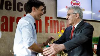 Prime Minister Justin Trudeau shakes hands with a man wearing a suit at the Parsian Fine Foods grocery store.