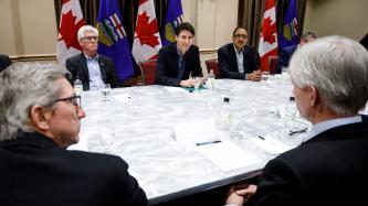 Prime Minister Justin Trudeau, Minister Amarjeet Sohi and Minister James Gordon Carr sit in a meeting with energy sector leaders alongside the flags of Canada and Alberta