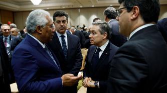 Prime Minister of Portugal, António Costa, speaks with Minister Champagne alongside two other men in a conference room full of people