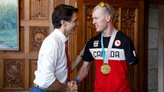 Prime Minister Justin Trudeau stands and shakes hands with Canadian Paralympic gold medalist Mark Arendz in his office