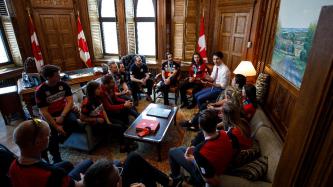 Prime Minister Justin Trudeau sits and speaks with a group of Canadian Olympians and Paralympians in his office