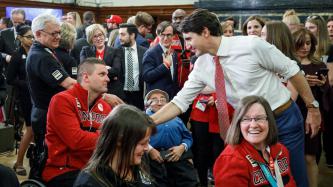 Prime Minister Justin Trudeau shakes hands with a Canadian Paralympian in a wheelchair while others look on in Parliament