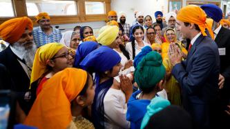Prime Minister Justin Trudeau greets a group of people wearing colourful traditional head coverings at Gurdwara Millwoods in Edmonton