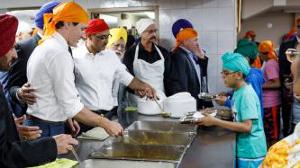 Prime Minister Justin Trudeau and Minister Amarjeet Sohi serve food in a cafeteria at Gurdwara Millwoods in Edmonton