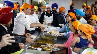 Prime Minister Justin Trudeau and Minister Amarjeet Sohi serve food in a cafeteria at Gurdwara Millwoods in Edmonton