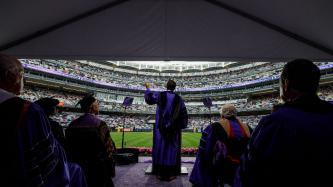 Prime Minister Justin Trudeau addresses a crowd of graduates from a podium on a stage in Yankee Stadium