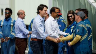 Prime Minister Trudeau shakes hands with workers outside.