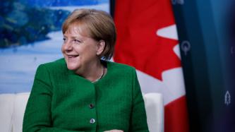 La chancelière Merkel est assise et sourit lors de la discussion.