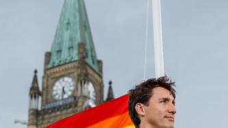 PM Trudeau stands in front of the Pride flag