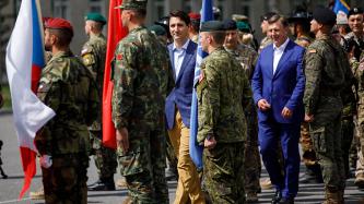 PM Trudeau and President Vējonis walk between military servicemen