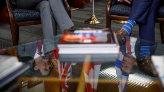 The faces of Prime Minister Trudeau and Toronto Mayor John Tory are reflected on a glass table during a meeting.