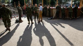 Le PM Trudeau, debout, mange en compagnie de militaires