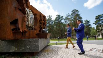 PM Trudeau and President Vējonis walk up to monument