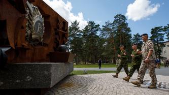 Three military servicemen walk up to monument