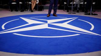 Prime Minister Trudeau stands on the NATO logo.