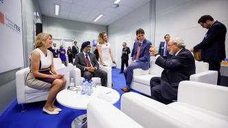 PM Trudeau, Ministers Freeland and Sajjan talk with people in a room.