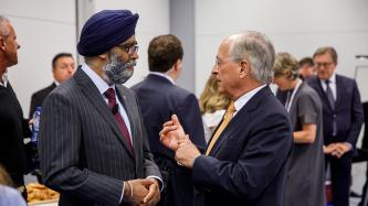 Minister Harjit Sajjan talks with a man in a room.