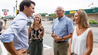 PM Trudeau smiles with three people with him on a sidewalk