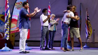 PM Trudeau and a man on stage exchange a hug