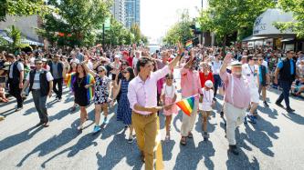 PM Trudeau waves to a crowd with a gay pride flag in hand