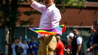 PM Trudeau waves to a crowd with a gay pride flag in hand