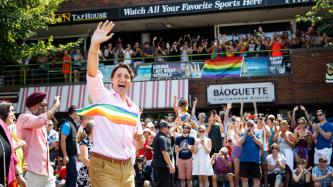 PM Trudeau waves to a crowd with a gay pride flag in hand