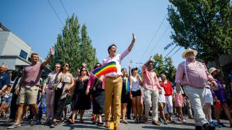 PM Trudeau waves to a crowd with a gay pride flag in hand