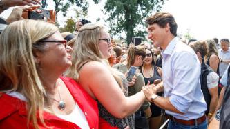PM Trudeau shakes hands with a woman in a large crowd