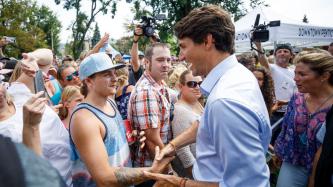 PM Trudeau shakes hands with a man in a large crowd