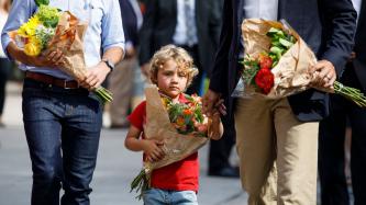 Hadrien porte des fleurs en tenant la main de son père
