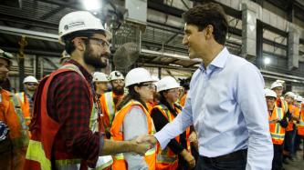 PM Trudeau shakes hands with an employee in a construction helmet