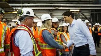 PM Trudeau shakes hands with an employee in a construction helmet
