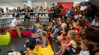 PM Trudeau sits on a stool and speaks to a group of children
