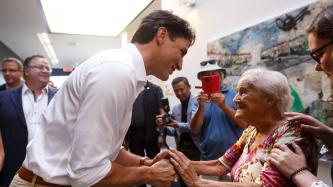 PM Trudeau shakes hands with an elderly woman