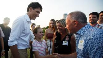 Ella-Grace shakes hands with a man while PM Trudeau looks on