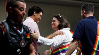 PM Trudeau embraces an attendee wearing a rainbow sash