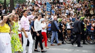 PM Trudeau and Sophie walk and smile and wave to the crowd