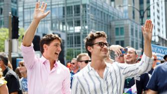 PM Trudeau and another man smile and wave to the crowd