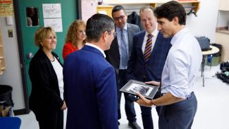 Le PM Trudeau tient un cadre en écoutant un homme parler