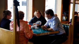 PM Trudeau sits with a group of women at a booth in the restaurant