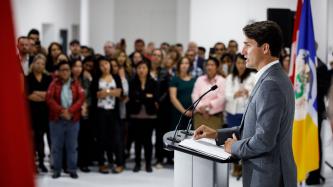 PM Trudeau stands at a podium and speaks