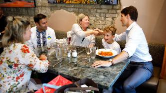 PM Trudeau and MP Arif Virani sit with a family at the restaurant