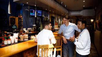 PM Trudeau and MP Arif Virani talk with a man sitting at the bar