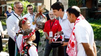 PM Trudeau and MP Arif Virani talk with young girls in traditional Polish dress