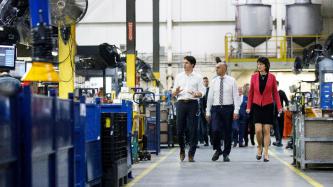 Le PM Trudeau marche en parlant avec un homme et une femme