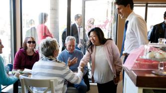 Minister Ng shakes hands with a woman while PM Trudeau and others look on