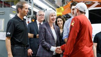 Minister Hajdu shakes hands with an employee while PM Trudeau and others look on