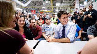 PM Trudeau smiles while listening to someone speak