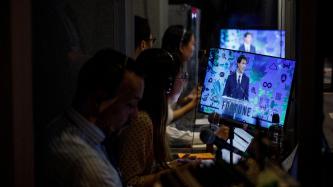 Une traductrice écoute le PM Trudeau via un moniteur en coulisse