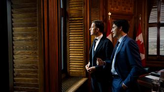 PMs Trudeau and Rutte talk while looking outside a window